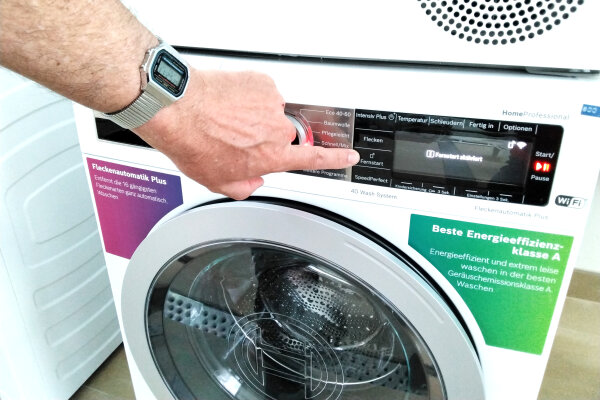 Person aktiviert den Fernstart einer Waschmaschine.