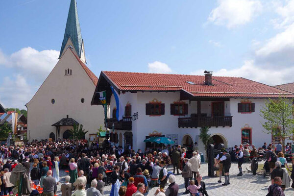 Ein Dorfplatz gefüllt mit vielen Menschen.