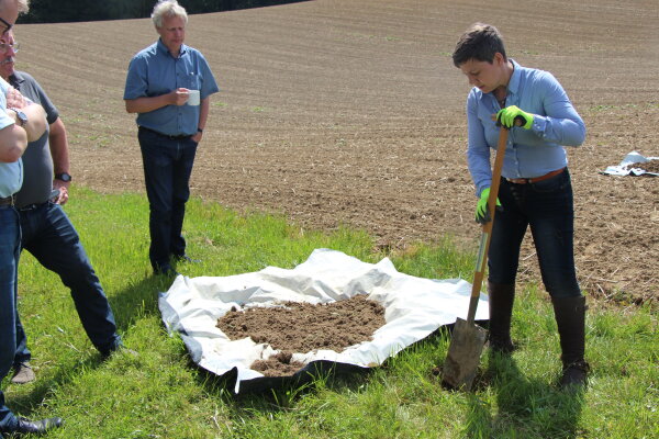 Personen neben einer Plastikplane auf die Erde geschaufelt wurde