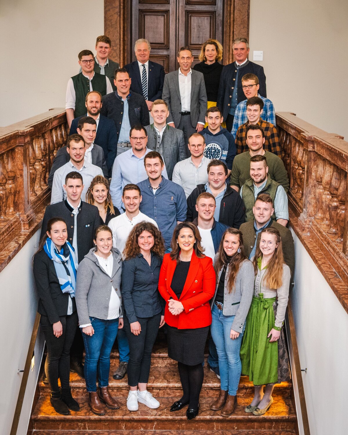 Staatsministerin Michaela Kaniber steht mit den bayerischen Top-Absolventinnen und -Absolventen auf einer Treppe.