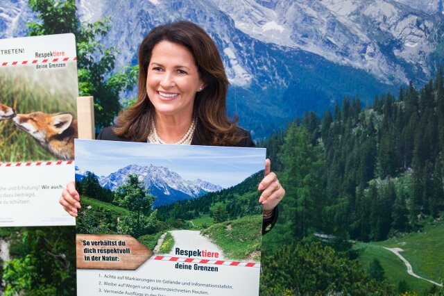 Ministerin Michaela Kaniber hält ein Schild der Initiative "Respektiere deine Grenzen" hoch.