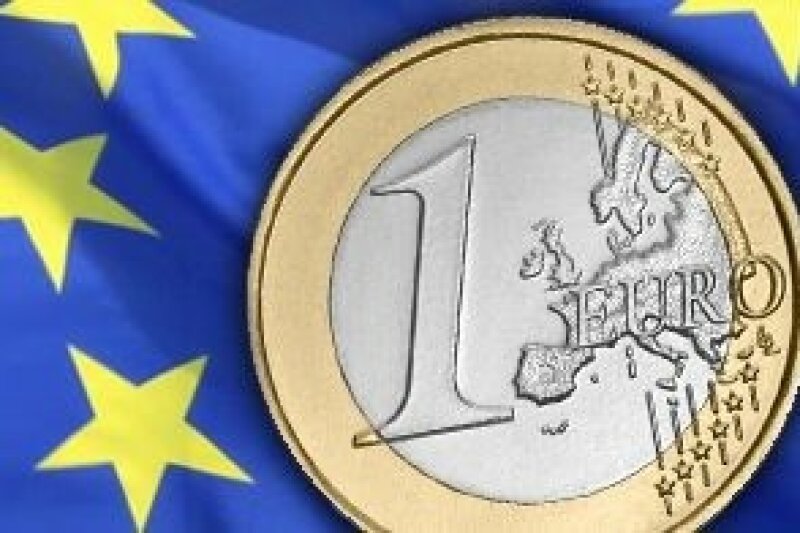 Ein Euromünze vor Europaflagge