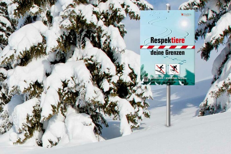 Schneebedeckte Tannen, dazwischen Schild mit Aufschrift "Respektiere deine Grenzen"