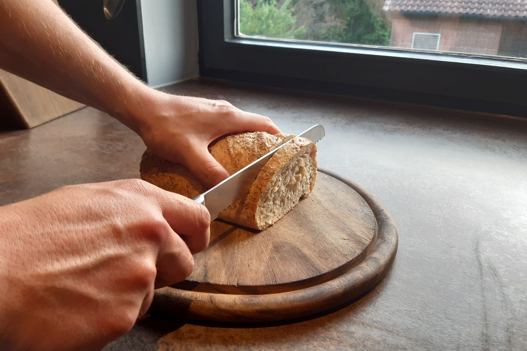 Eine Person schneidet Brot auf einem Holzbrett