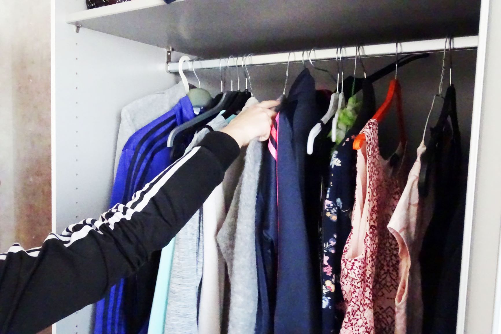 Eine Person nimmt Kleidung aus dem Kleiderschrank.