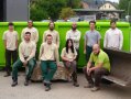Neun Männer und eine Frau vom Preisträger-Team Johannes Lang – Gärten vor einem grünen Kontainer.