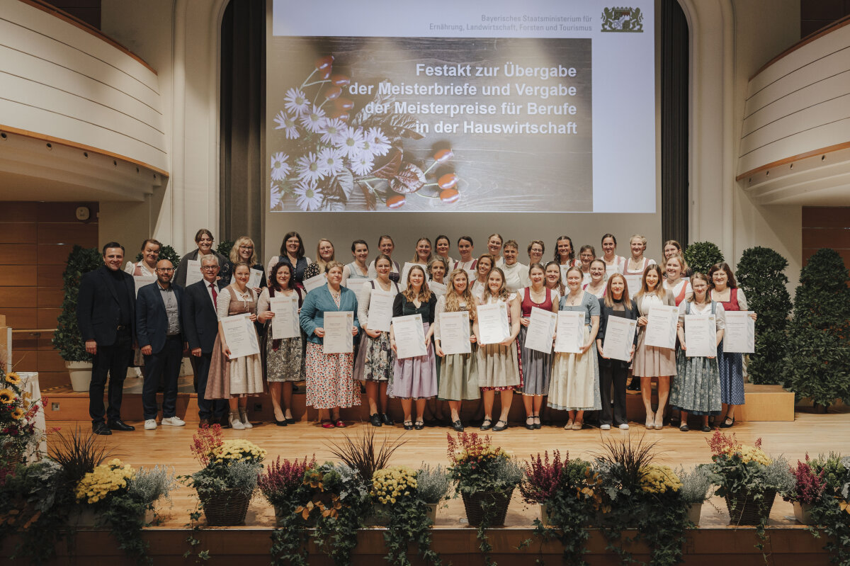 Gruppenfoto mit allen Absolventinnen, Amtschef Hubert Bittlmayer und zwei weiteren Männern.