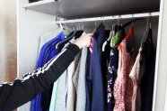 Eine Person sortiert Kleider auf einen Kleiderbügel