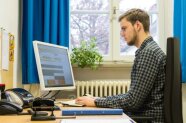 Ein junger Mann tippt etwas in einen Computer ein