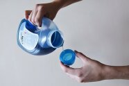 Person portioniert Flüssigwaschmittel in Dosierkappe