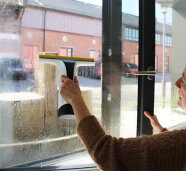 Eine Frau putzt ein Fenster mit einem Waschroboter