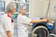 Zwei junge Frauen stehen an einer industriellen Waschmaschine