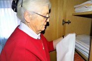 Eine Seniorin räumt Wäsche in einen Schrank