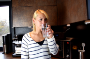 Eine junge Frau trinkt ein Glas Leitungswasser