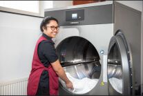 Eine junge Frau befüllt eine industrielle Waschmaschine