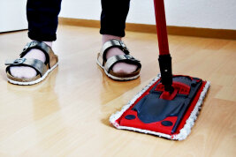 Eine Person putzt einen Boden mit einem Mopp