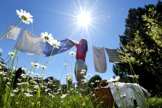Frau hängt draußen Wäsche an eine Wäscheleine.