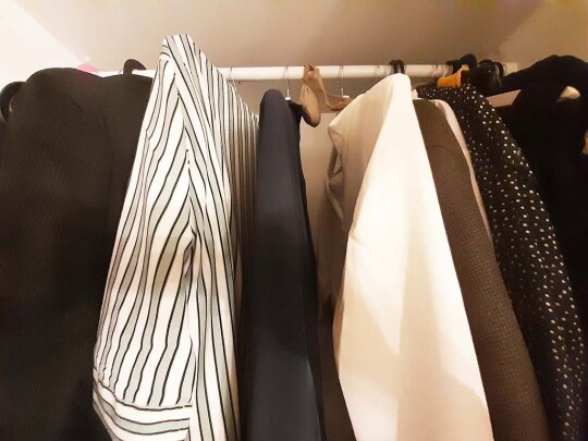 Ein offener Schrank, in dem Hemden hängen.