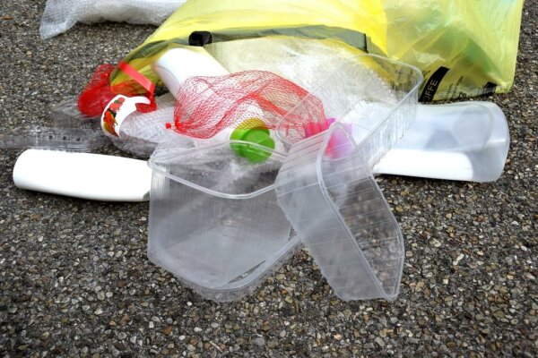 Verschiedener Plastikmüll wie Obstschalen, Flaschen und Luftpolsterfolie auf einem Boden.