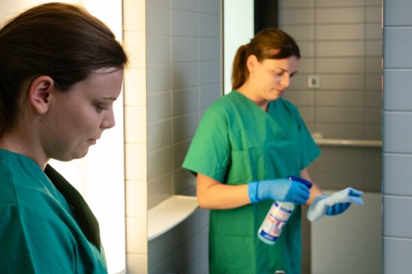 Eine Hauswirtschafterin reinigt den Spiegel im Sanitärbereich.
