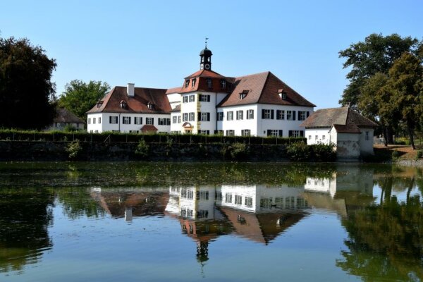 Außenansicht Weißes Schloss Triesdorf, das sich in einem Gewässer spiegelt