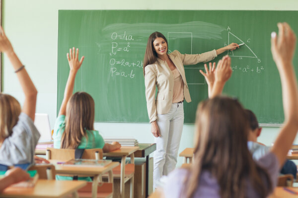 Eine Lehrerin an einer Tafel, vor ihr Schulkinder