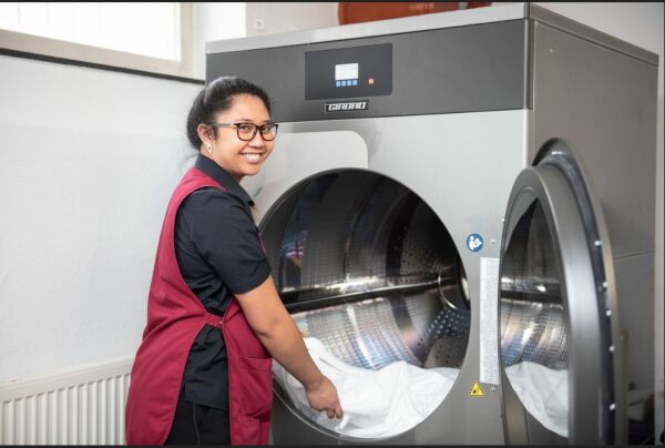 Hauswirtschafterin an einer industriellen Waschmaschine.