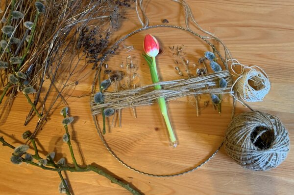 In einen Metallkranz mit Garn in der Mitte wird ein Reagenzglas mit Tulpe gesteckt.