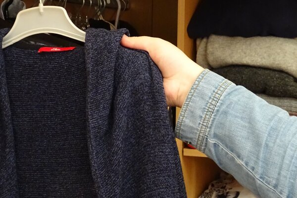 Eine Person nimmt Wäsche aus einem Kleiderschrank.