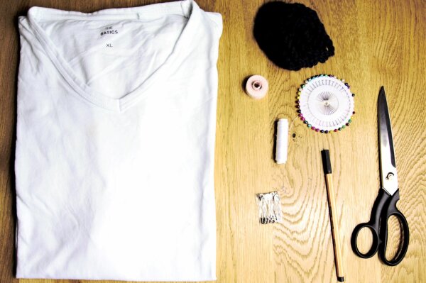 T-Shirt, Schere, Kordel, Stecknadeln, Stift, Sicherheitsnadeln und Maßband auf Tisch