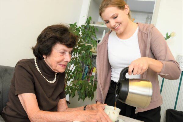 Eine junge Frau schenkt einer älteren Dame Kaffee ein