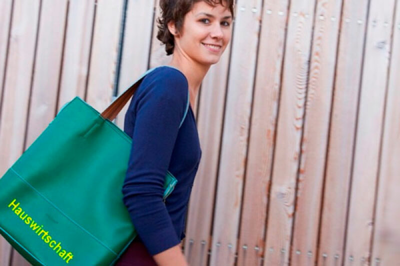 Junge Frau trägt Tasche mit Aufschrift Hauswirtschaft unter ihrem Arm