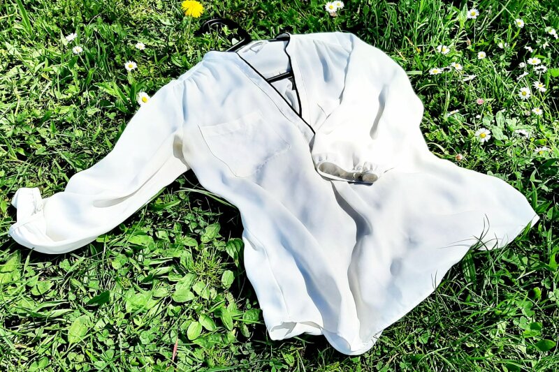 Weiße Bluse liegt im Gras