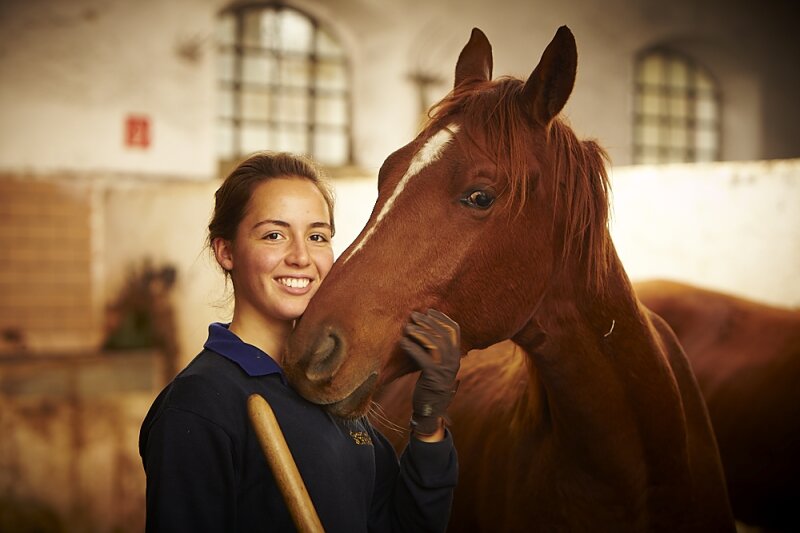 lächelnde Frau streichelt ein Pferd am Kopf