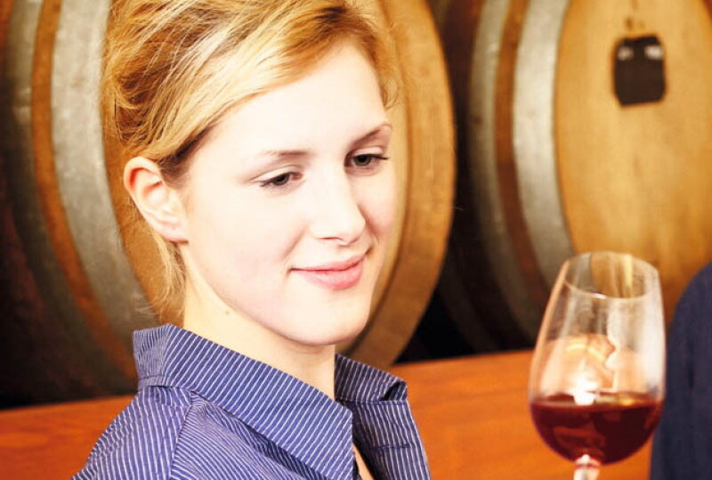 Winzerin hält ein Glas Rotwein in der Hand