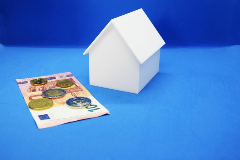 Ein weißes Modellhaus vor dem Geld liegt