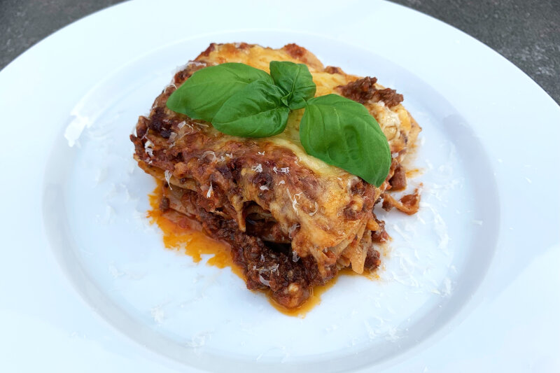 Lasagne auf einem Teller mit Basilikum angerichtet