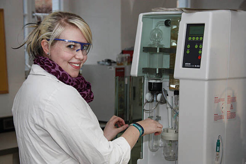 Frau mit Schutzbrille und weißem Kittel in einem Labor