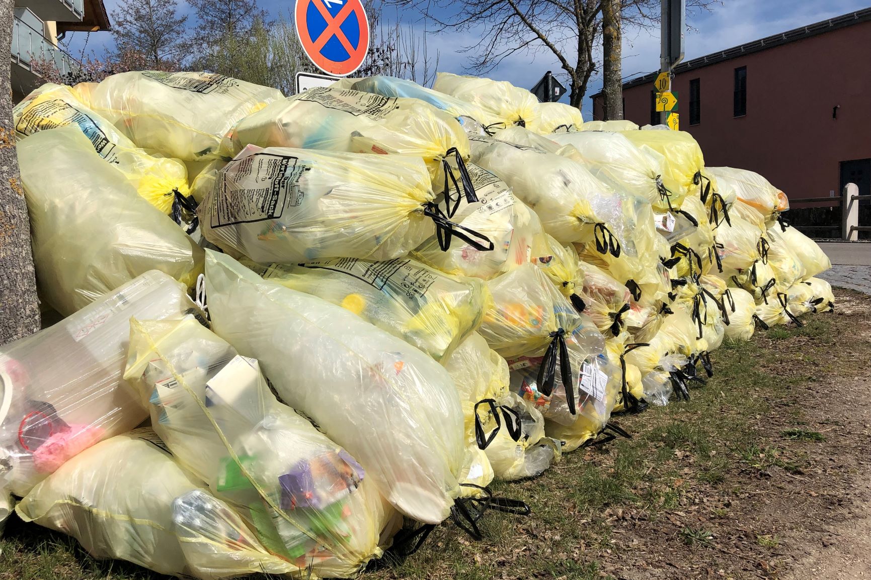 Ein großer Stapel gelber Säcke an einer Straße.