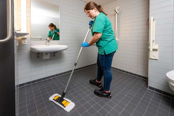 Eine Person wischt einen Fließen-Boden mit einem Wischmopp.