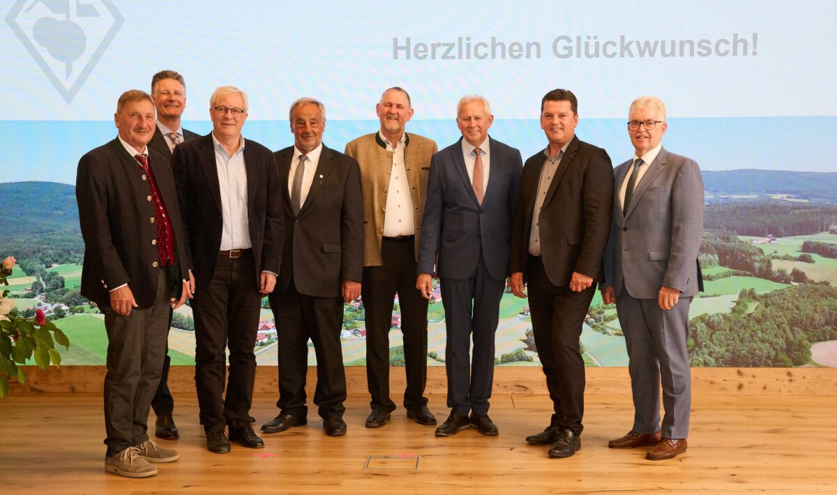 Das Bild zeigt Amtschef Hubert Bittlmayer zusammen mit den Ausgezeichneten vor einer LED-Wand im Veranstaltungssaal des Ministeriums. 