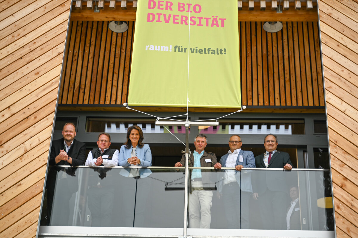 Das Bild zeigt Staatsministerin Kaniber zusammen mit den Teilnehmenden der Eröffnung des Hauses für Biodiversität. Sie stehen nebeneinander auf auf dem Glasbalkon des Hauses.