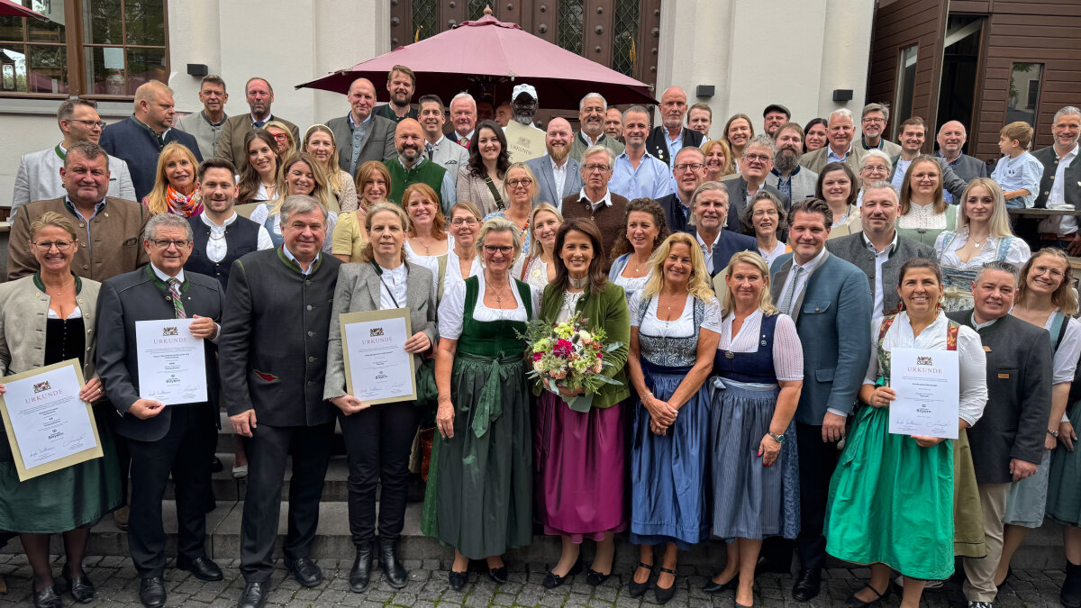 Das Bild zeigt Staatsministerin Kaniber zusammen mit DEHOGA-Präsidentin Angela Inselkammer mit den prämierten Gastronomie- und Festzeltbetreibern. Einige der Prämierten halten Urkunden in der Hand.
