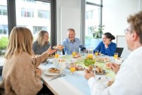 Mehrere Personen sitzen bei gemeinsamen Essen zusammen