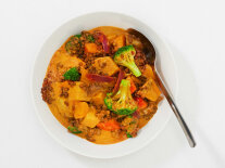Currygericht mit Brokkoli, Linsen und anderem Gemüse in einem weißen Teller