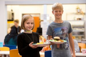 Ein Mädchen und ein Junge halten je einen Teller mit Essen in der Hand