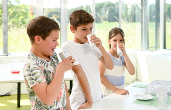 3 Kinder stehen hinter Tisch und riechen an Gefäßen