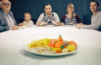 Teller mit Essen auf einem Tisch - im Hintergrund Personen verschiedenen Altersftsverpflegung
