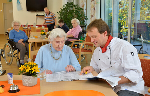 Koch bespricht mit Seniorin den Speiseplan