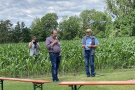 Landwirt mit Mikrofon vor einem Maisfeld